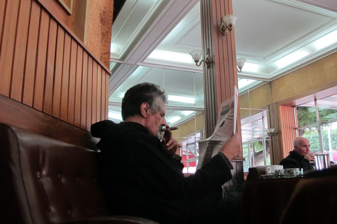Reading paper with cigar in Cafe de Paris