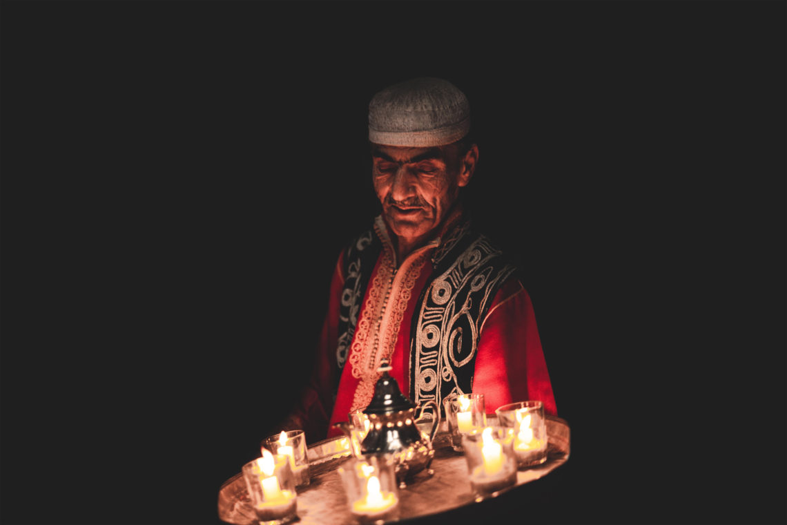 Bashir holding a tray of candles. Photograph by Will Rijnbout.