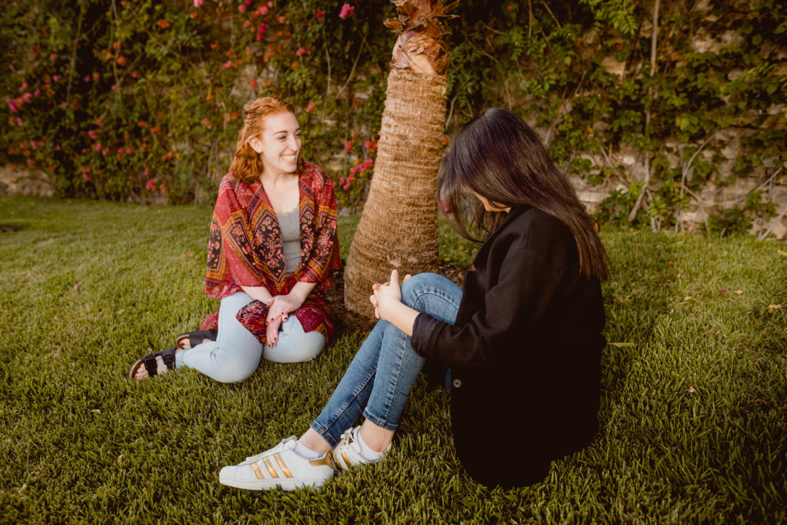 Caitlyn and Rania sitting beneath a palm tree.