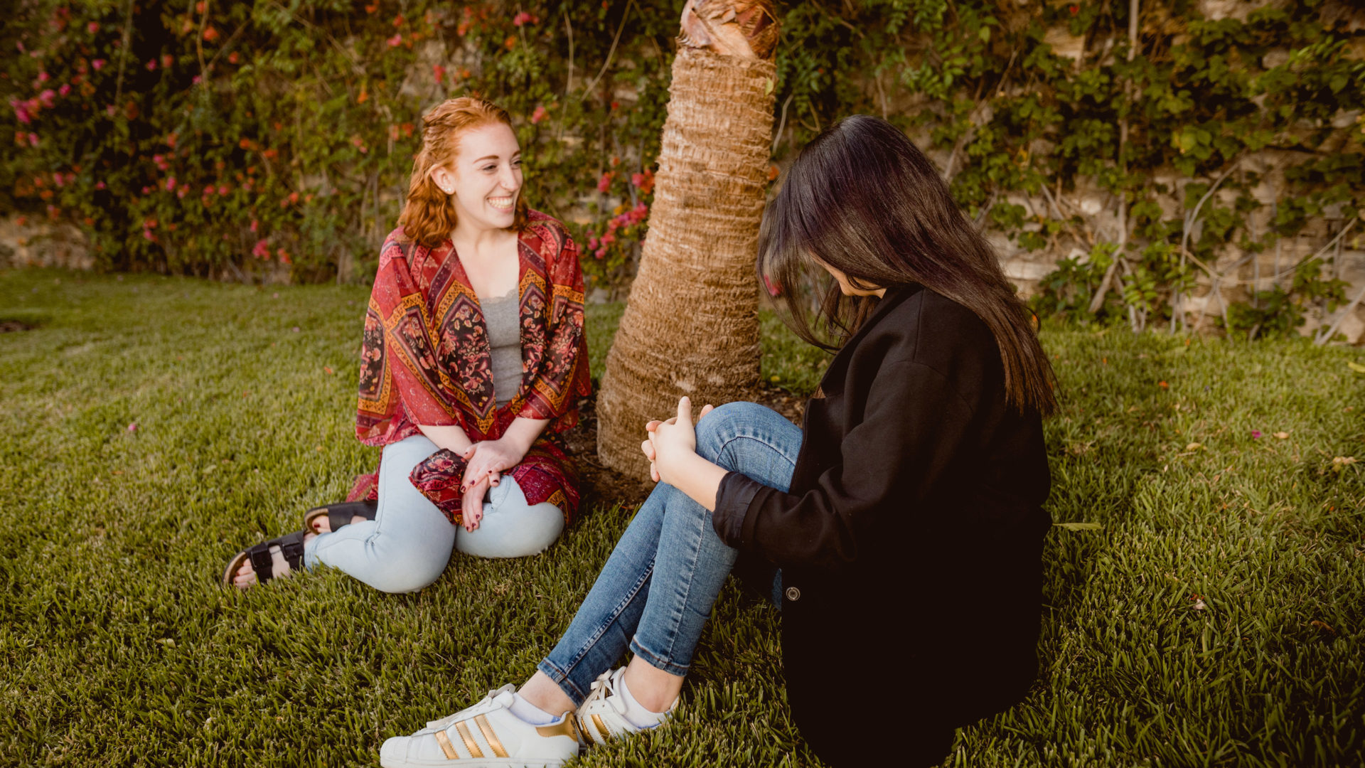 Caitlyn and Rania sitting beneath a palm tree.